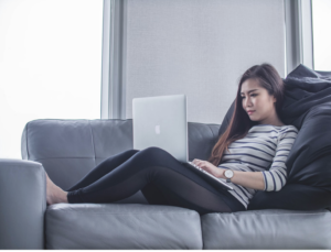 A woman on a couch looks at a laptop